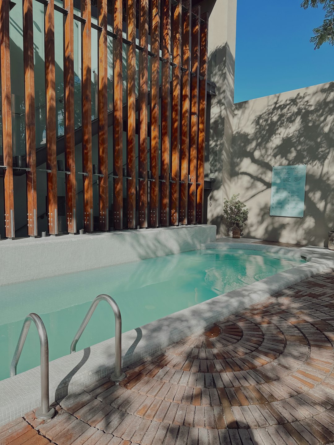 Okrągłe jacuzzi na zewnątrz stoi obok nowoczesnego drewnianego budynku.